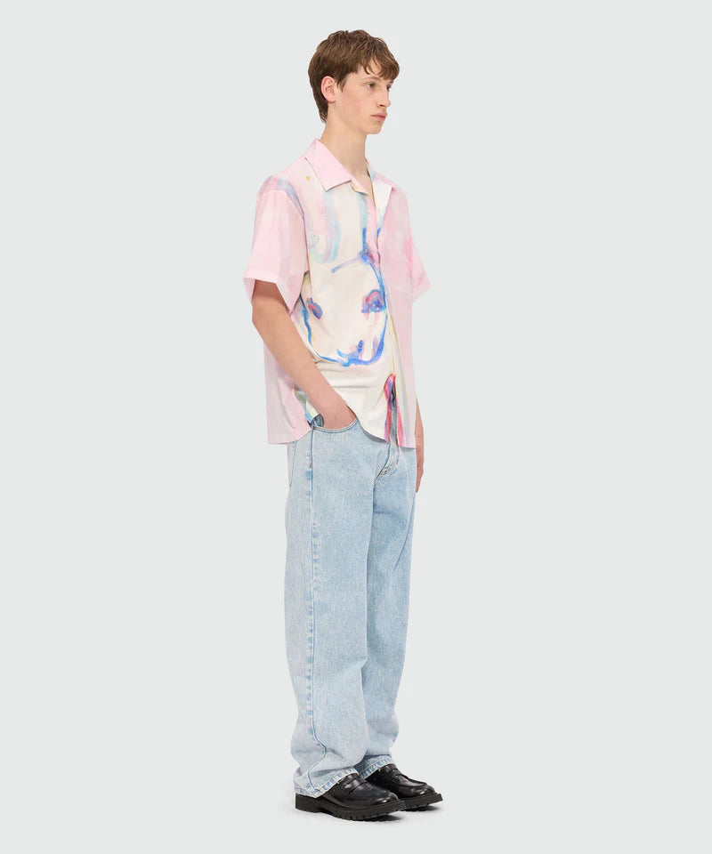 Model wearing oversized pink poplin bowling shirt with The White Rabbit print and jeans.