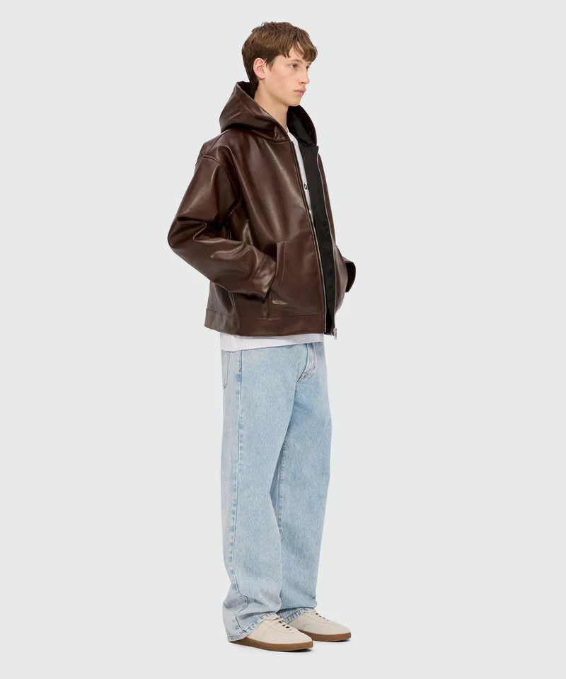 Model wearing a brown textured faux leather hooded jacket with kangaroo pocket and metal zip closure.