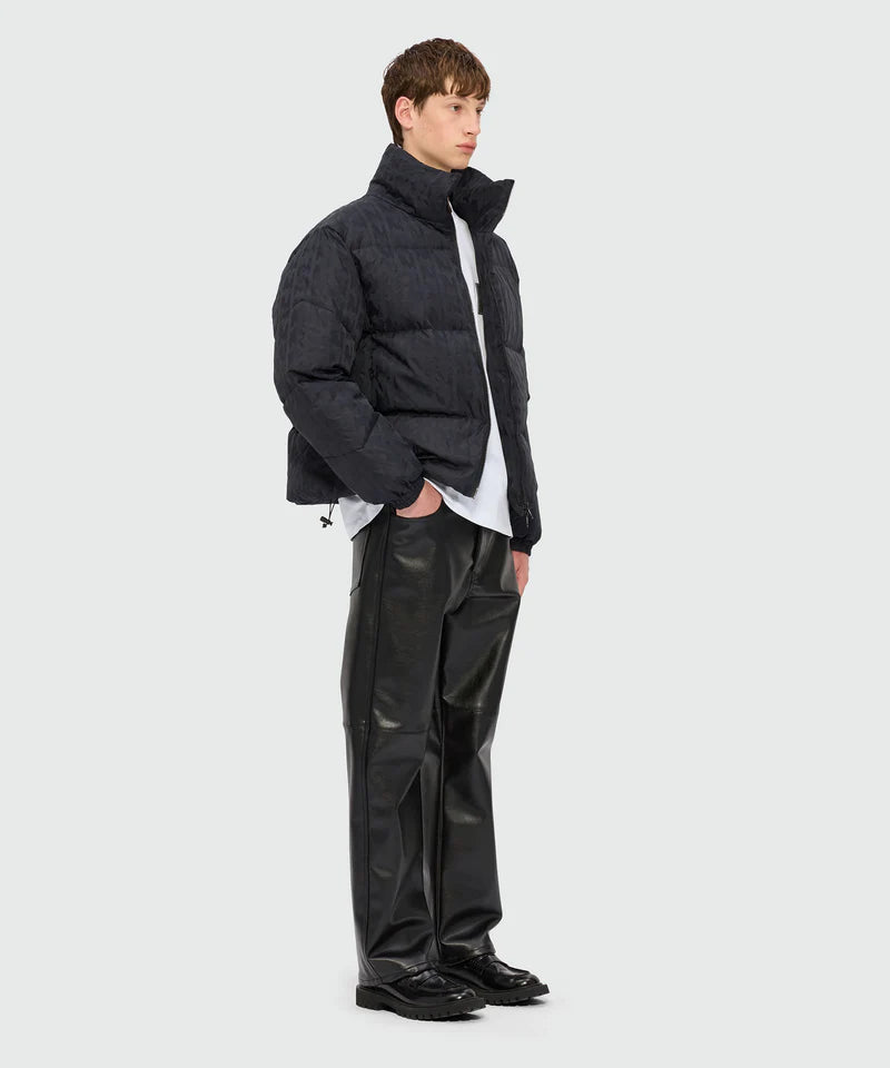 Model wearing a black puffer jacket with high collar paired with sleek leather trousers and a white crew-neck T-shirt.