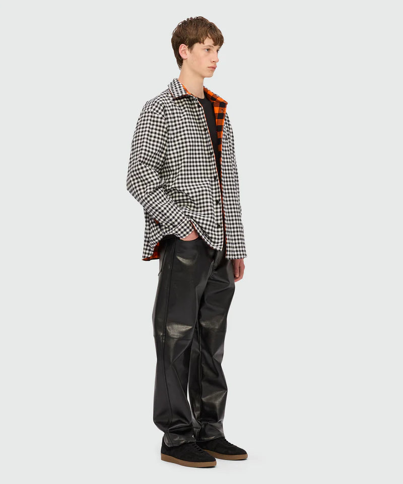 Model wearing a black and white checkered jacket with black faux leather pants, showcasing contemporary streetwear style.