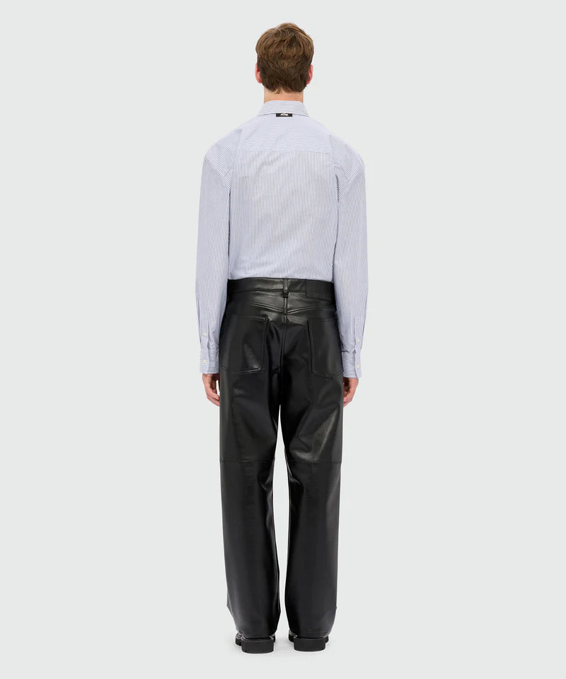 Model wearing black textured faux leather trousers with oversized fit, five-pocket styling, and MSGM logo patch.