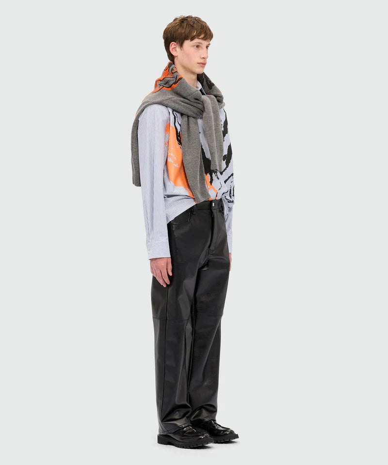Model wearing black textured faux leather trousers with oversized fit and five-pocket styling.
