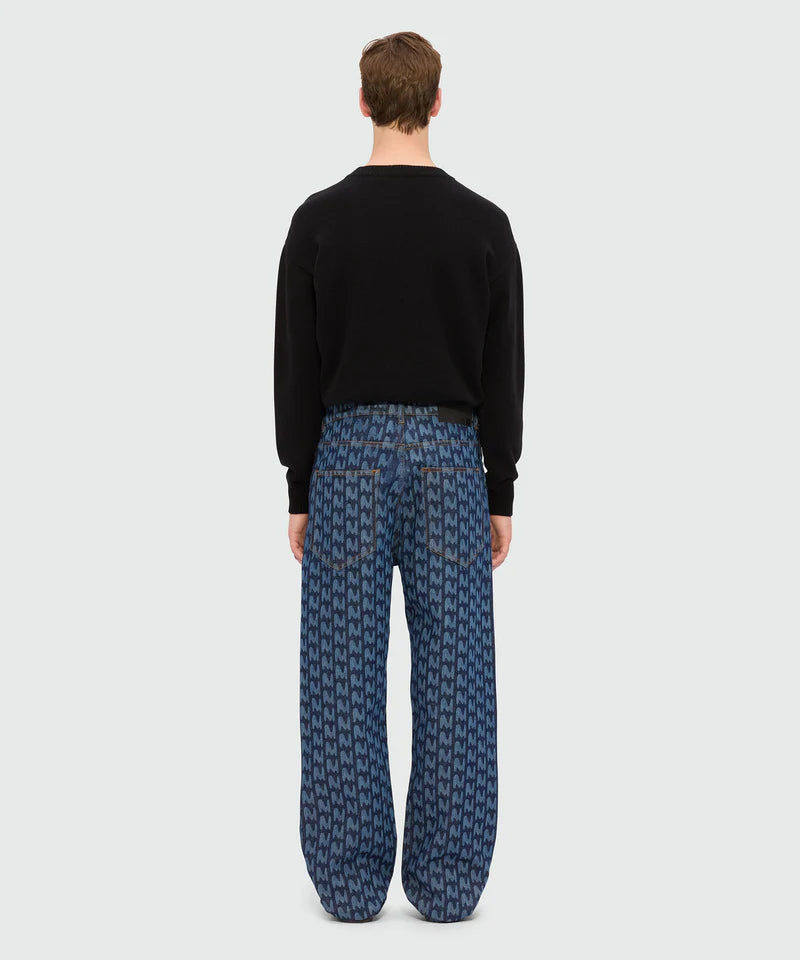 Back view of model wearing blue laser-cut denim trousers with TheMwave motif and oversized fit.