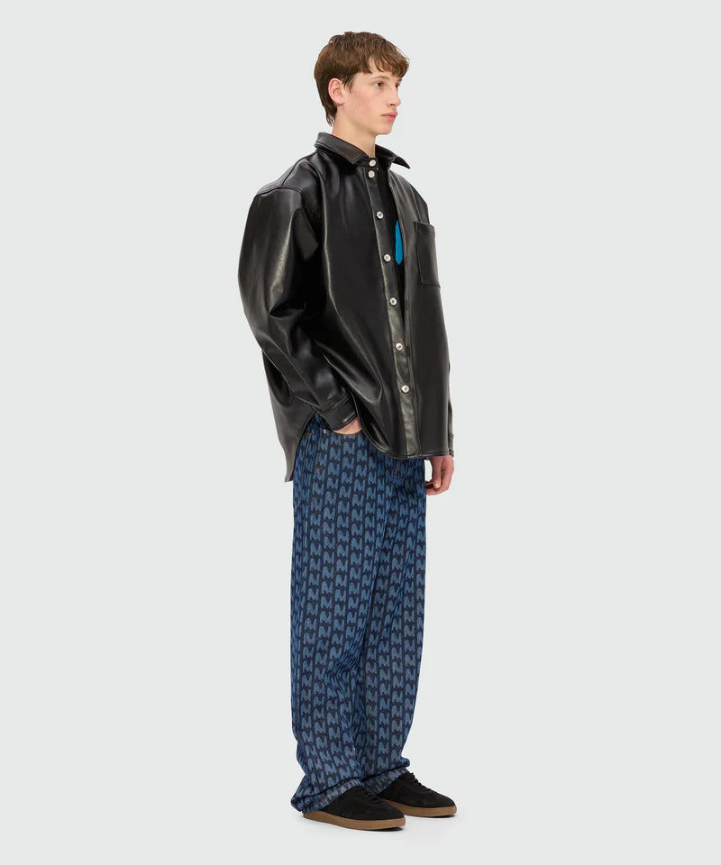 Man wearing oversized black leather shirt with blue laser-cut denim trousers featuring 'TheMwave' motif.