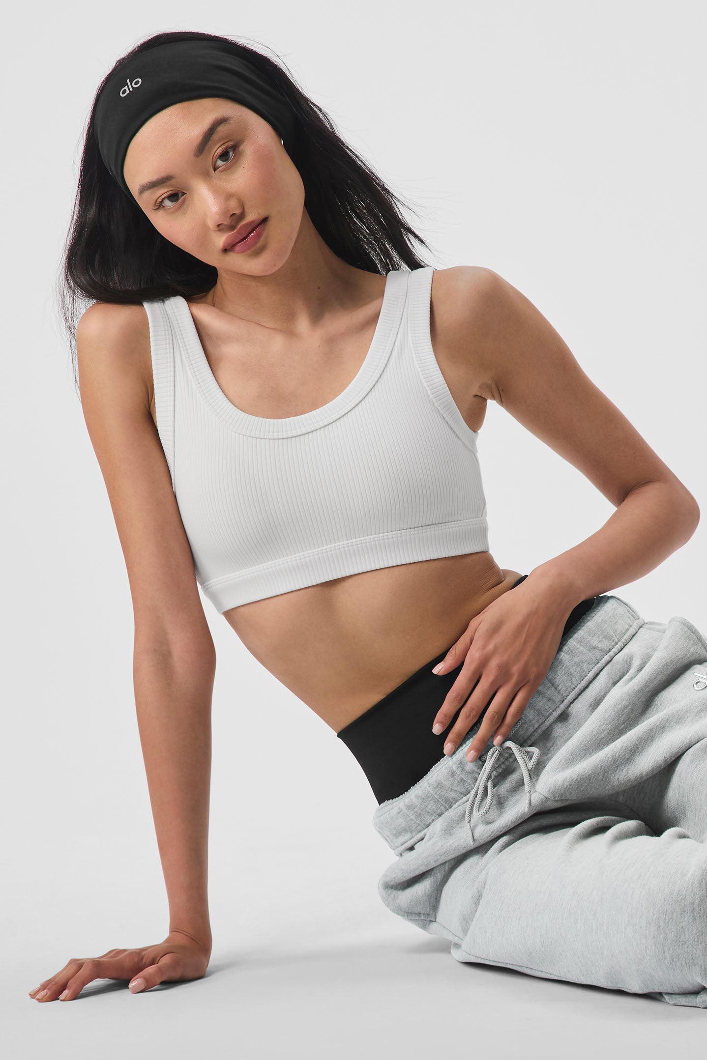 Model wearing the Airlift Headband with a white crop top and gray sweatpants, showcasing its sleek performance fabric design.