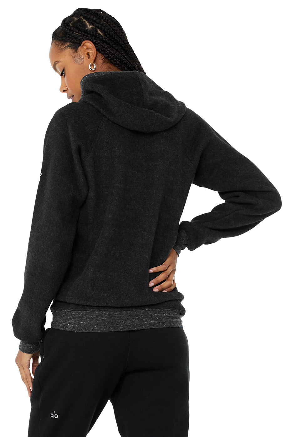 Back view of a woman wearing the Triumph Hoodie in black, showcasing its cozy fleece material and hood design.