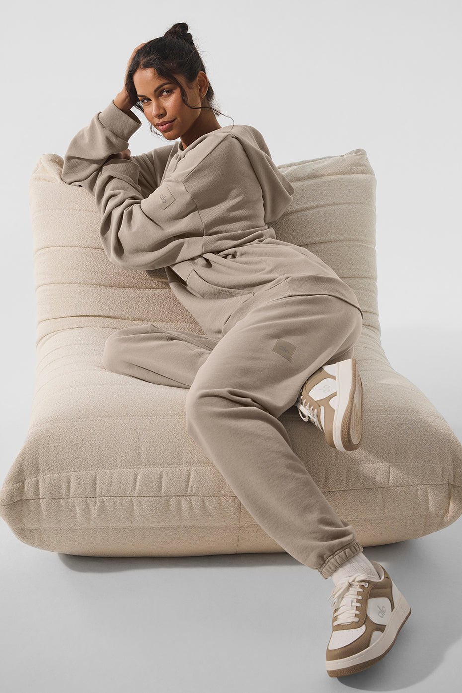 Woman in Chill Vintage Wash Hoodie and sweatpants relaxing on a large cushion, showcasing casual vintage style and comfort.