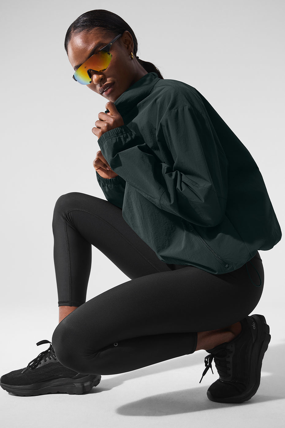 Model wearing Light Weight Takeaway Track Pullover with quarter-zip, relaxed fit, and zippered pockets, styled with leggings.