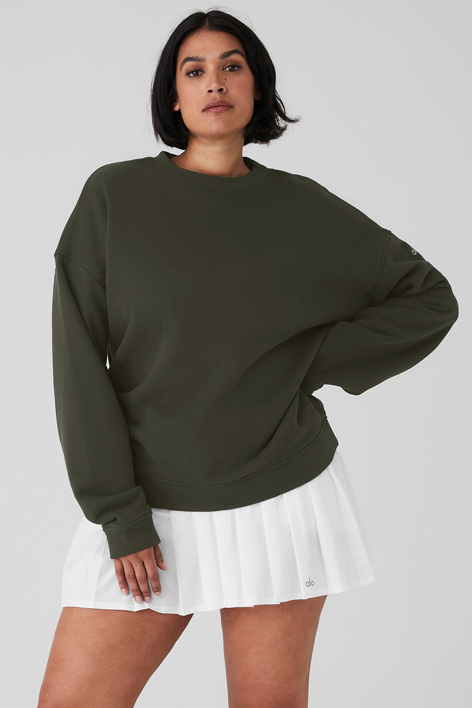 Woman wearing Renown Heavy Weight Crew Neck Pullover in green with oversized fit paired with a white pleated skirt.