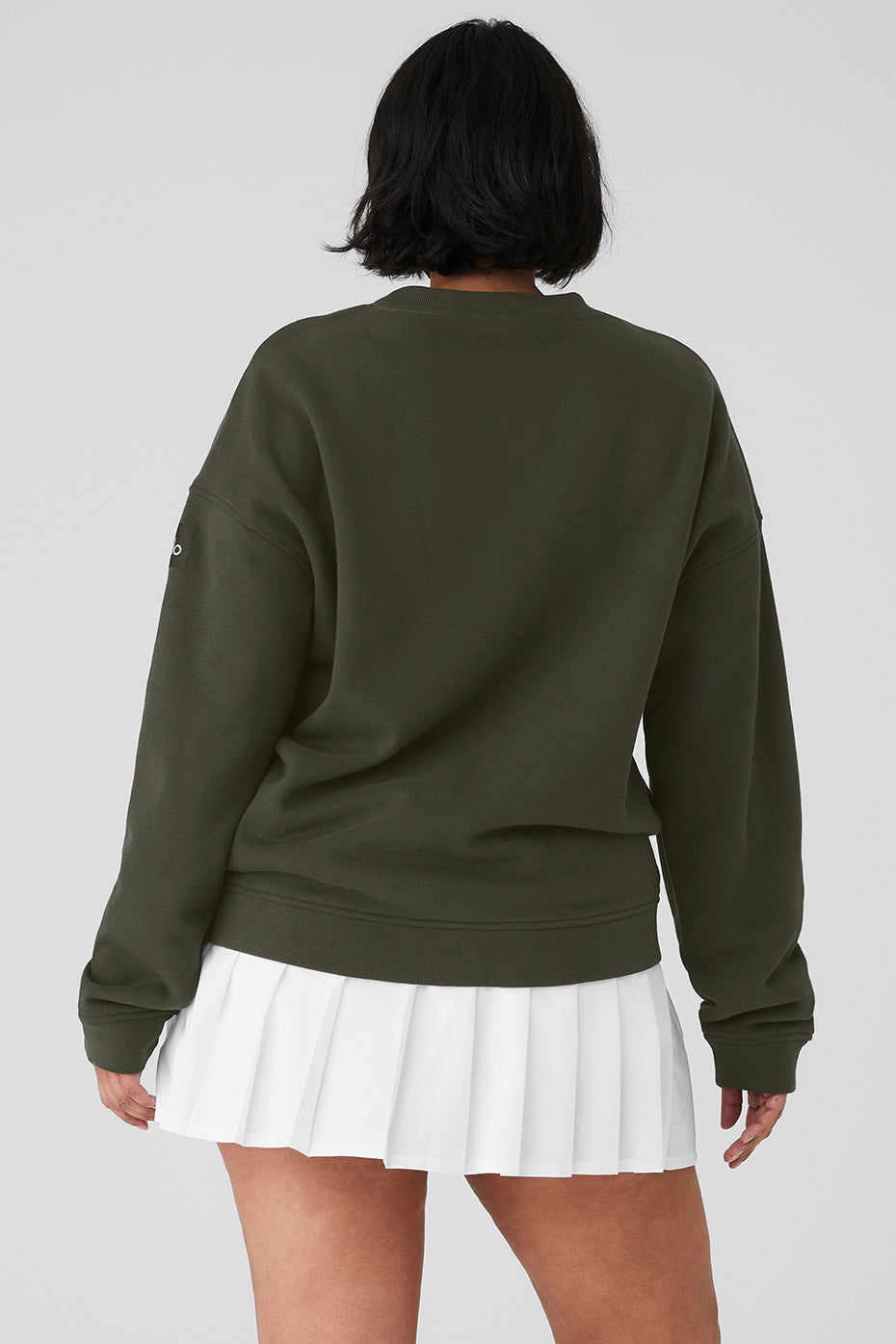 Rear view of a woman wearing a Renown Heavy Weight Crew Neck Pullover with dropped shoulders and white pleated skirt.