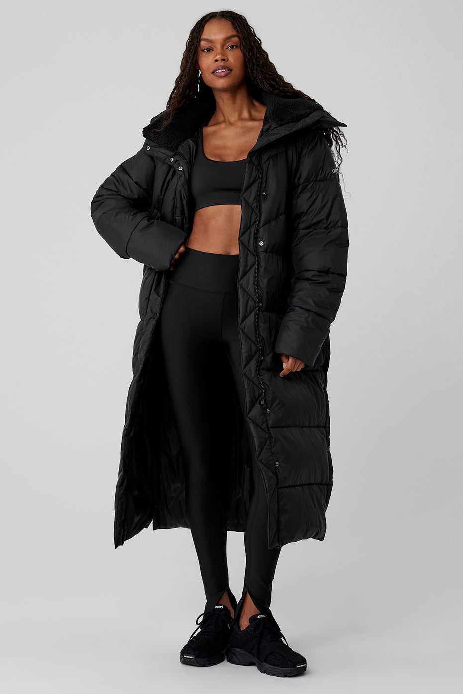 Model wearing a black Gold Rush puffer trench coat with oversized fit and sherpa-lined collar, perfect for cold winter weather.