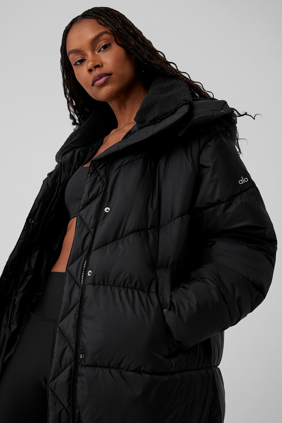 Model showcasing a black oversized puffer trench coat with a sherpa-lined collar, perfect for winter warmth.