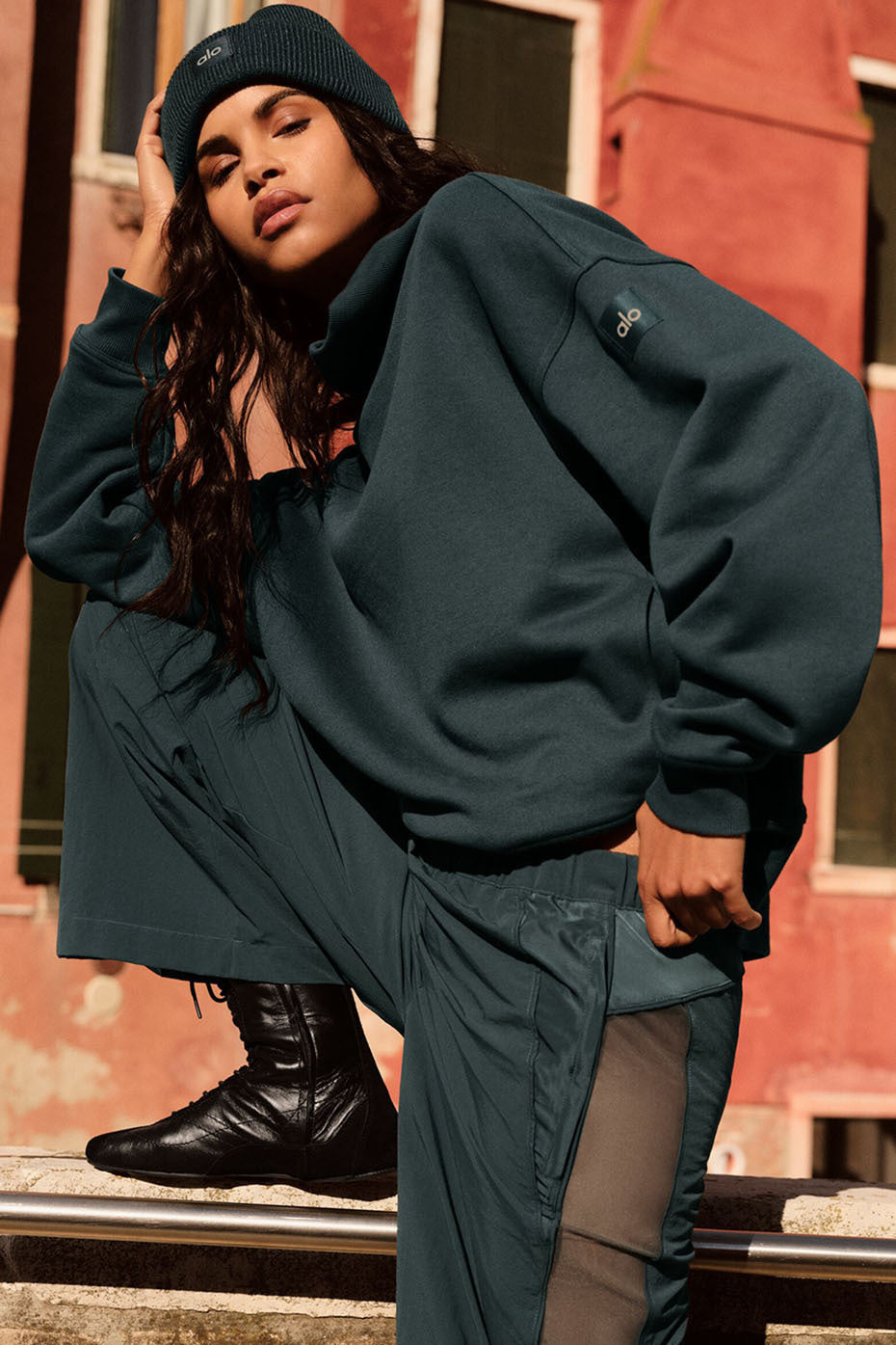 Model wearing a dark green hazy mock neck pullover with cargo pants and a beanie, showcasing a cozy oversized fit.
