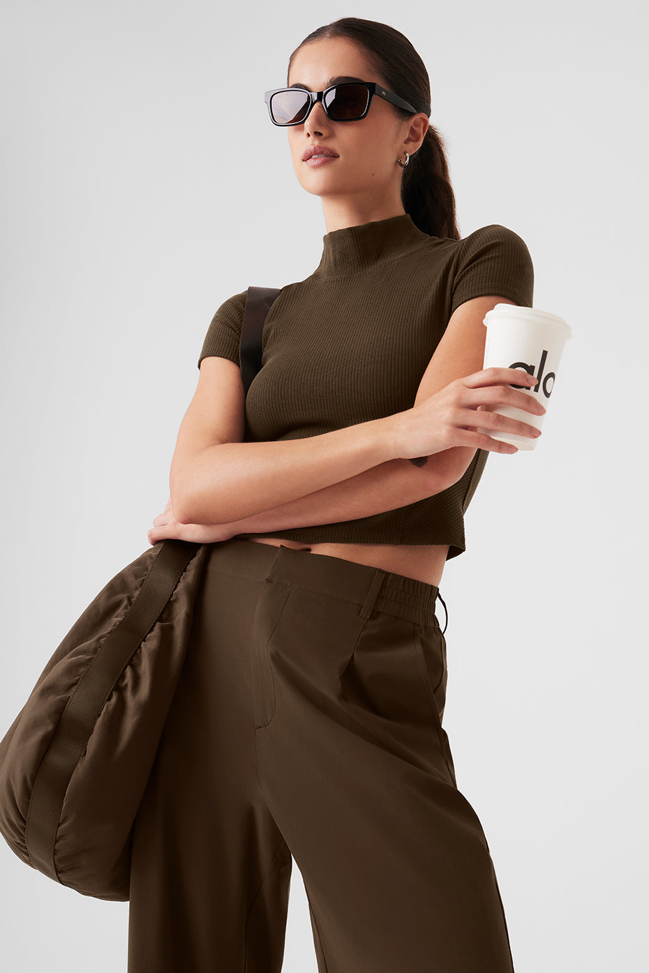 Woman in mock neck short sleeve rib tee with stylish bag and coffee cup, showcasing elevated basic fashion.