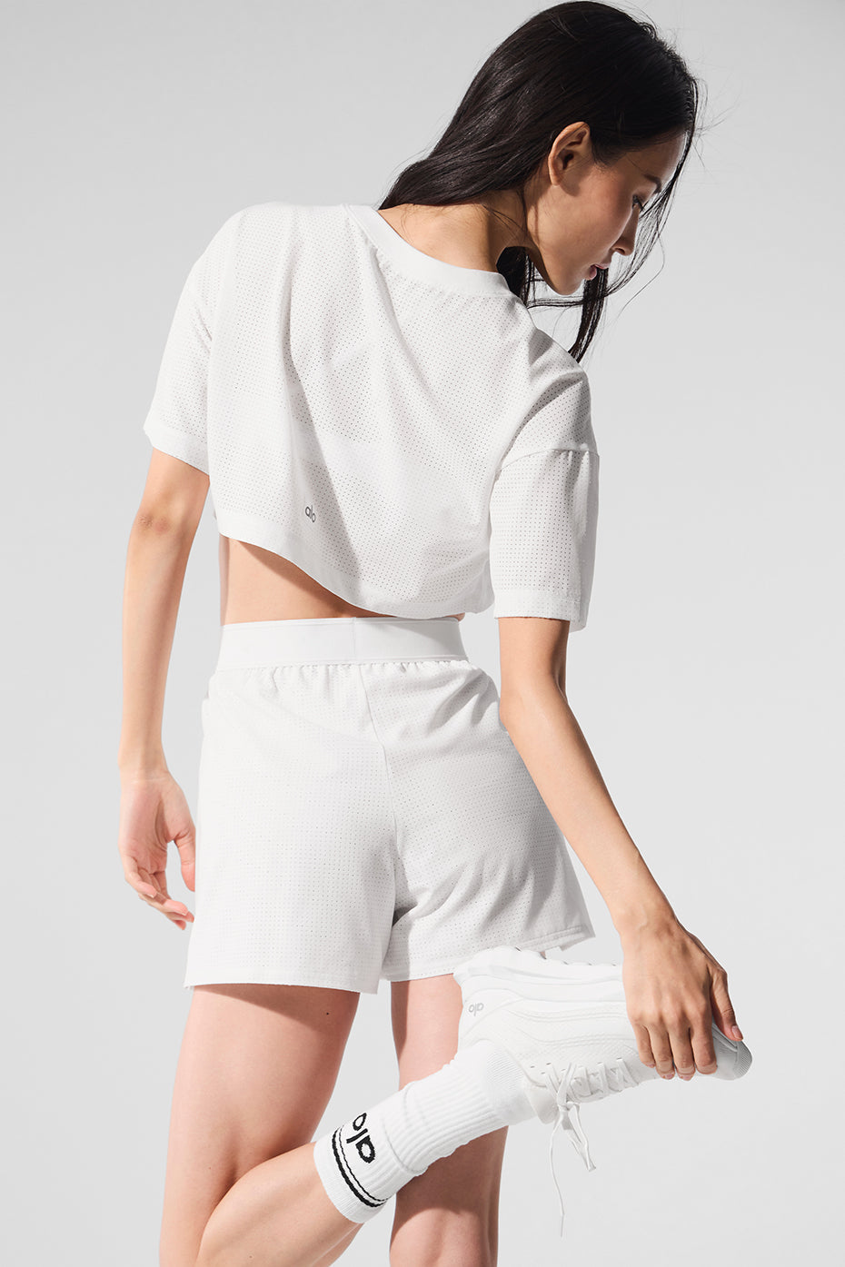 Model showcasing the Mesh Cropped Mirage Tee with lightweight fabric, styled casually with shorts and sneakers.