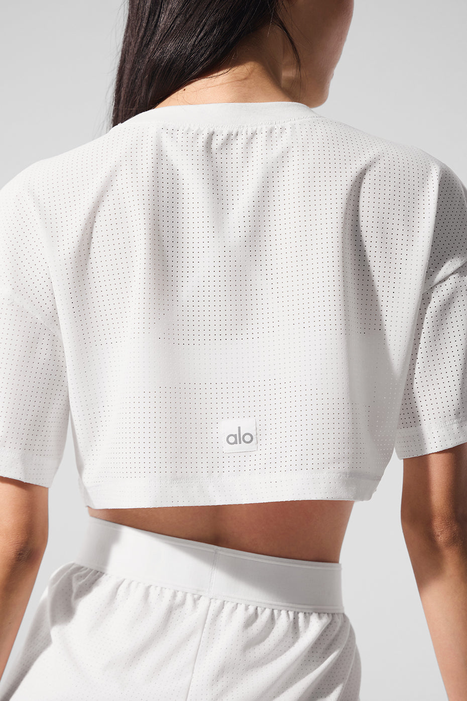 Model wearing a Mesh Cropped Mirage Tee displaying its lightweight perforated fabric and relaxed cropped fit.