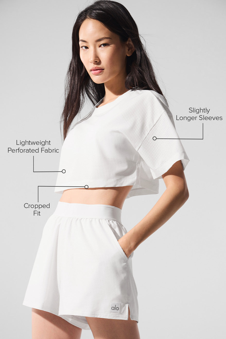 Model wearing the Mesh Cropped Mirage Tee made of lightweight perforated fabric with cropped fit and longer sleeves.