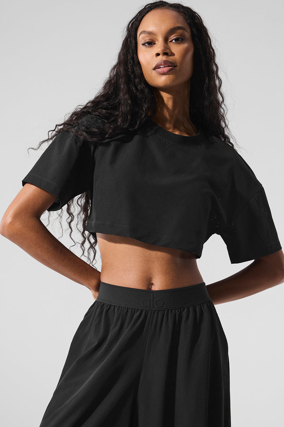 Model wearing black Mesh Cropped Mirage Tee with longer sleeves, showcasing a relaxed fit for casual summer style.