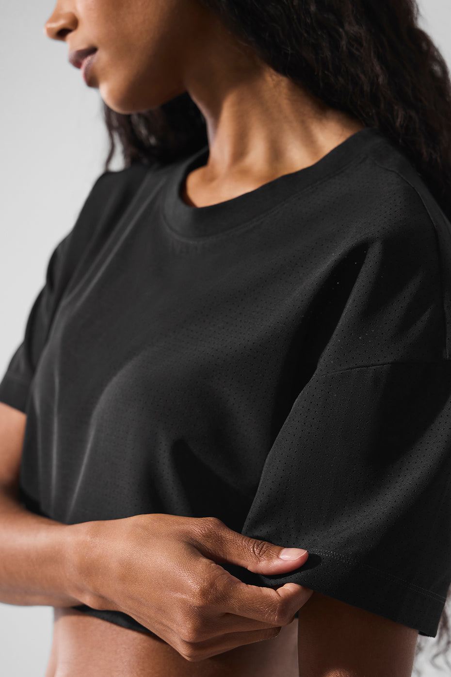 Model showcasing the Mesh Cropped Mirage Tee in black, highlighting its lightweight breathable fabric and relaxed cropped fit.