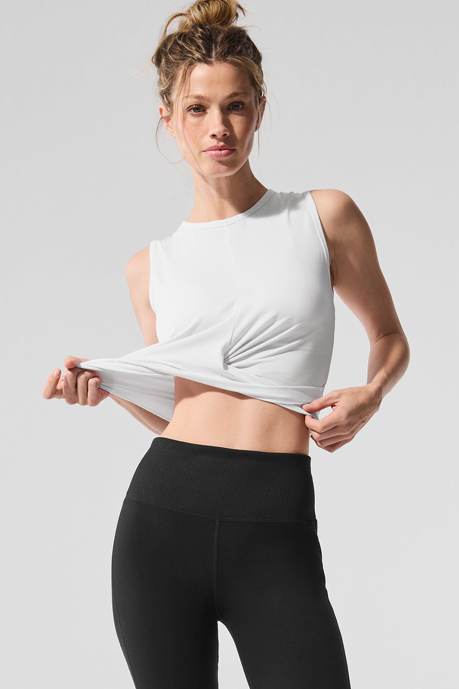 Model showcasing a fitted Cover Tank with a front wrap detail and raw edge finish, paired with black leggings.