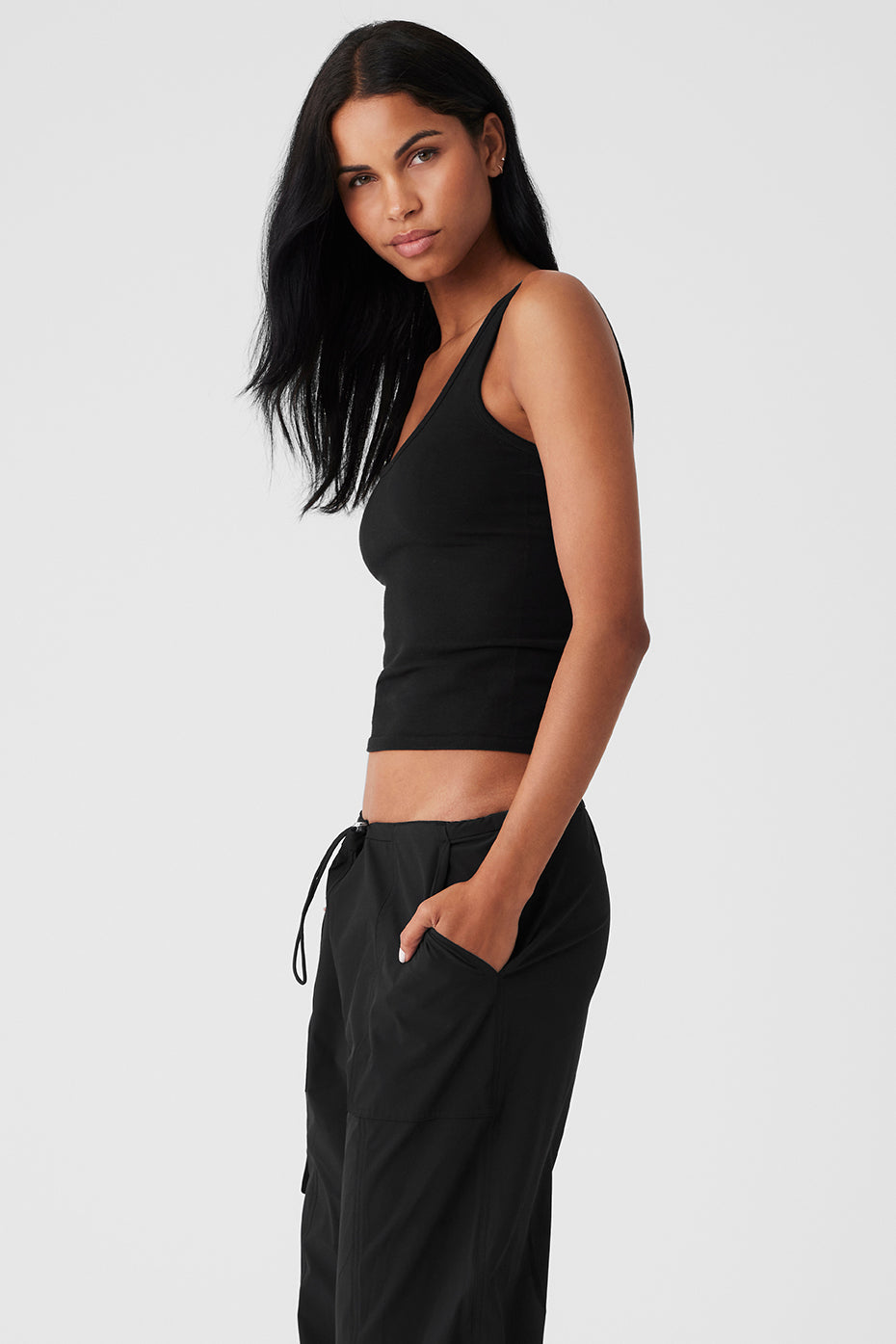 Model wearing a black seamless chosen tank top with a fitted silhouette and scoop neckline, paired with casual black pants.