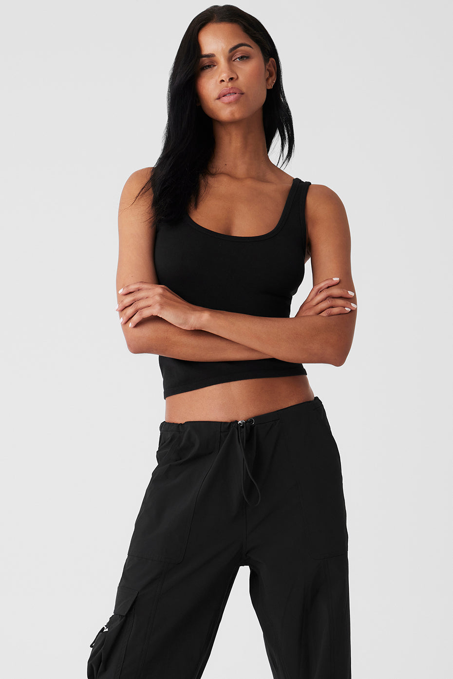 Woman wearing a black Seamless Chosen Tank, showcasing its fitted silhouette and deep scoop neckline, paired with casual pants.