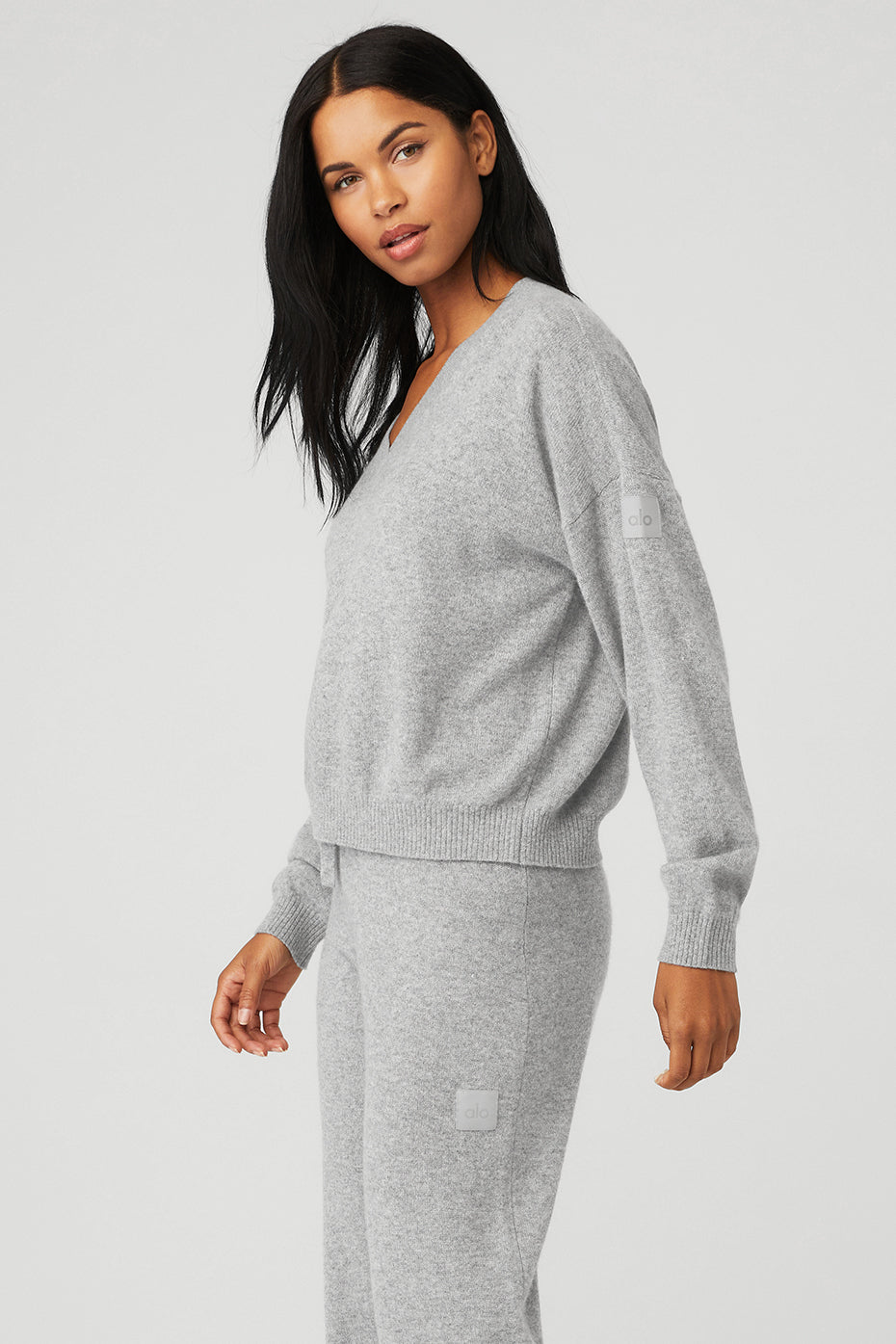 Model wearing Cashmere Jet Set V-Neck Pullover in gray with dropped shoulders and ribbed details.