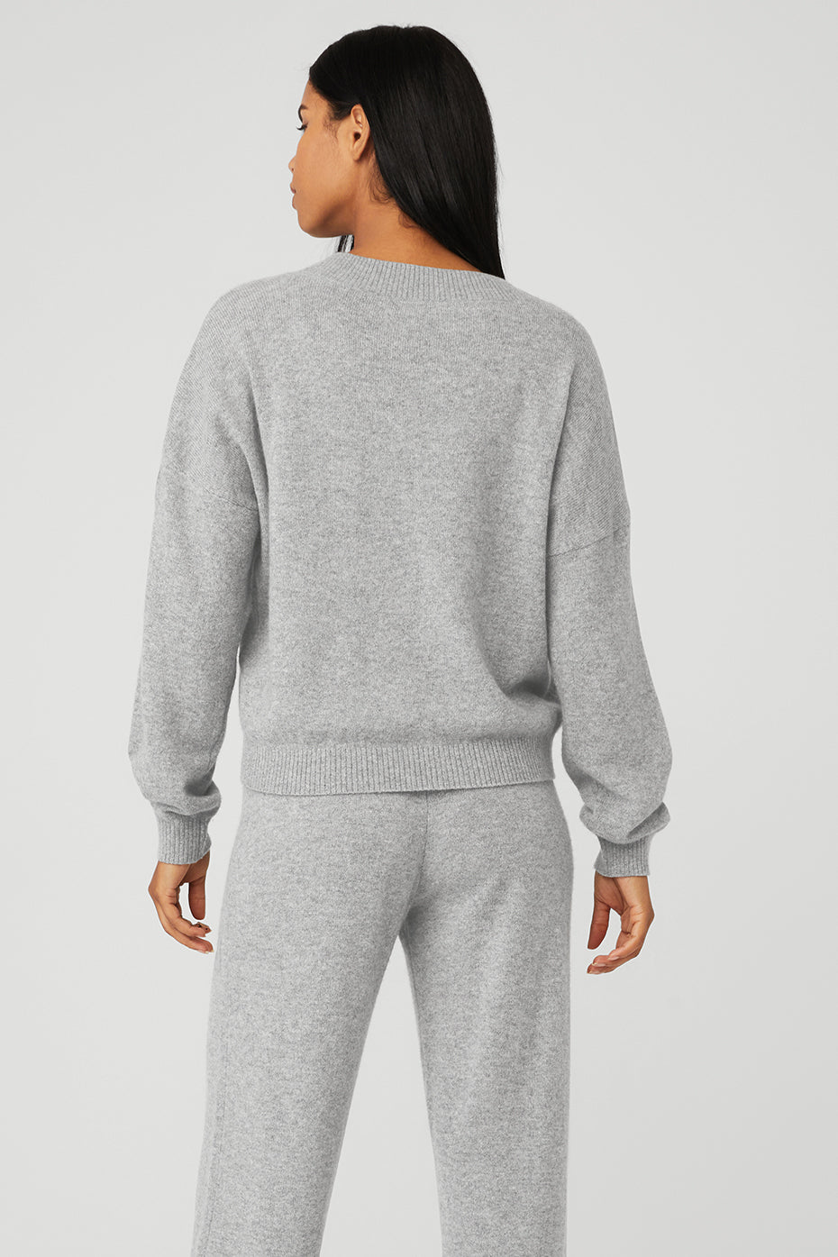 Back view of a woman wearing a soft gray Cashmere Jet Set V-Neck Pullover with dropped-shoulder design and ribbed cuffs.