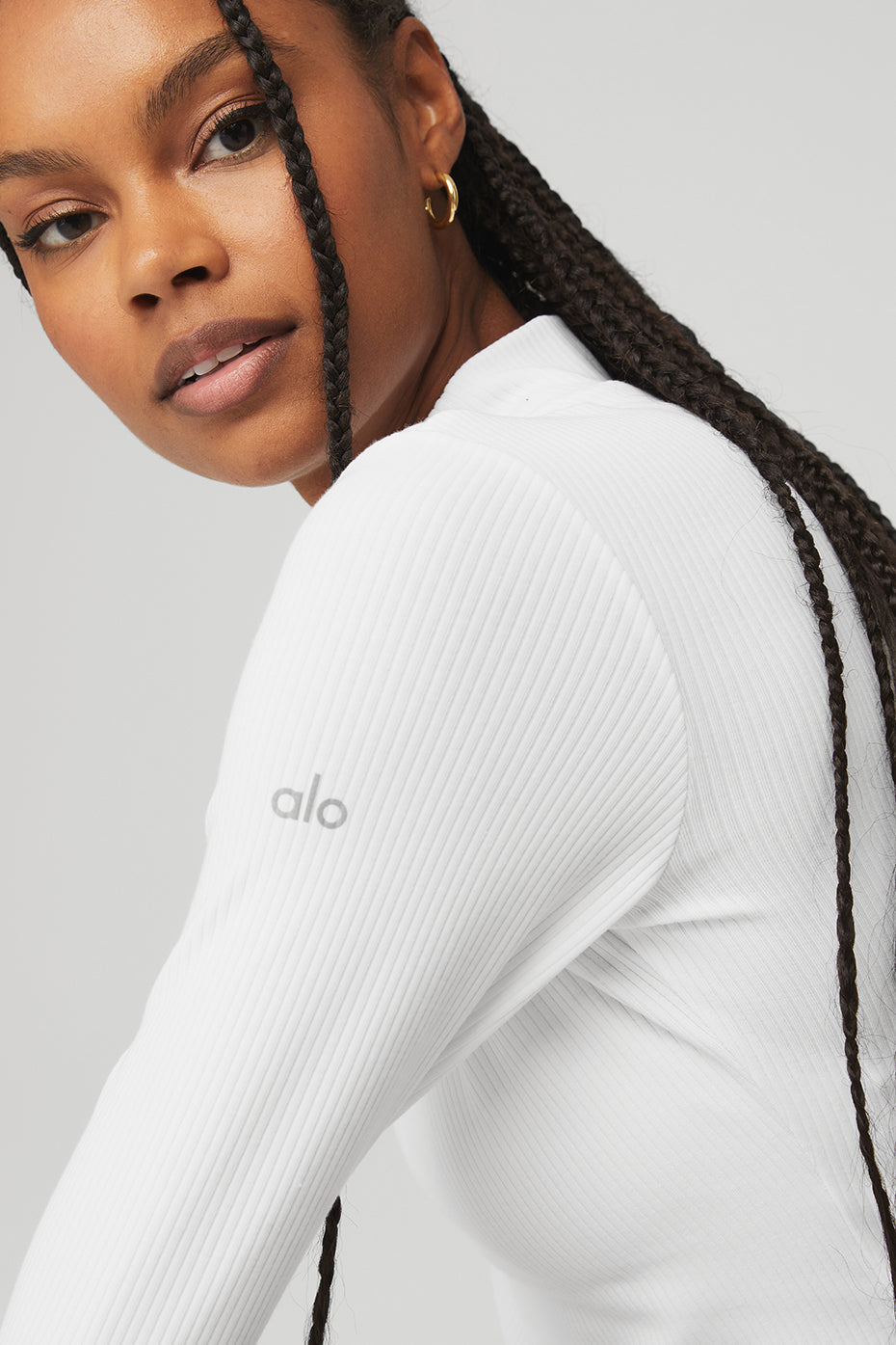 Model wearing the white Wellness Rib Mock Neck Long Sleeve top, showcasing its ribbed fabric and trendy design.