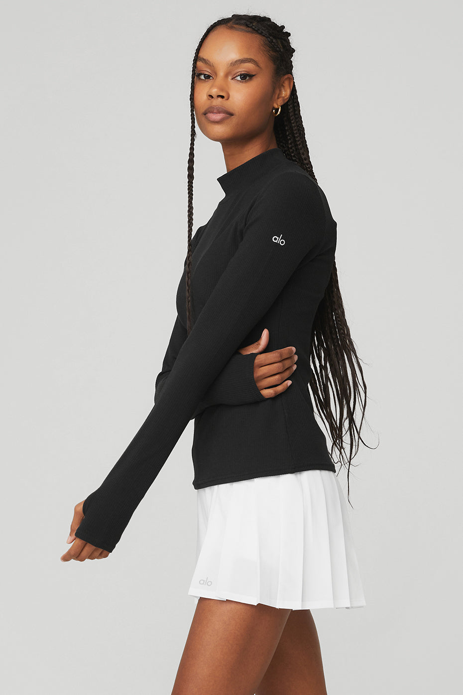 Wellness Rib Mock Neck Long Sleeve in black, styled with a white pleated skirt, showcasing a sleek, comfy look.