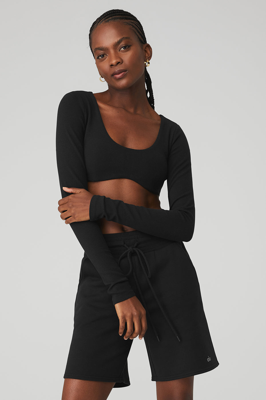 Model wearing a ribbed defined long sleeve bra top with scoop neck and black shorts, showcasing comfort and style.