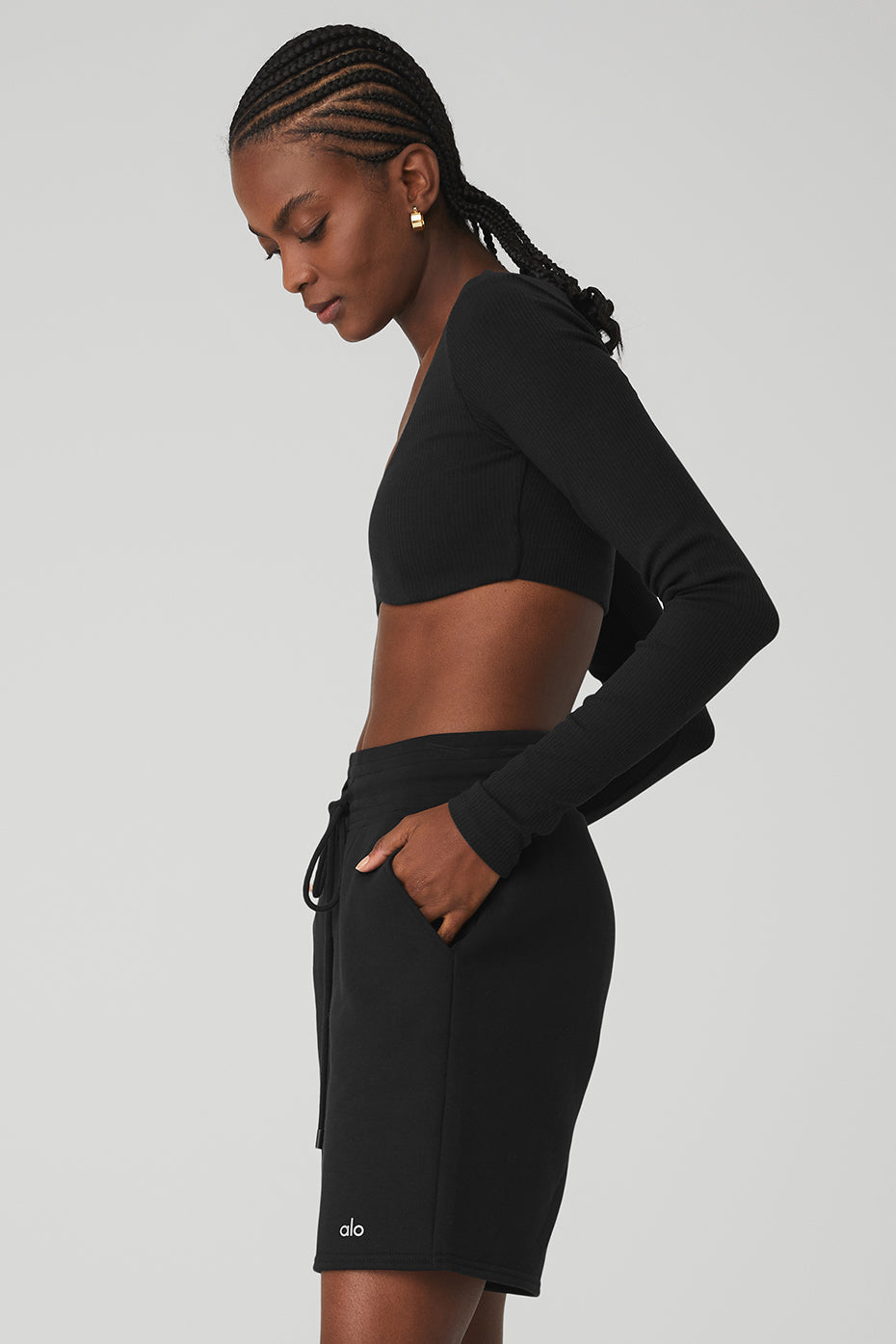 Model wearing a ribbed defined long sleeve bra in black, paired with black shorts, showcasing stylish and comfy sportswear.