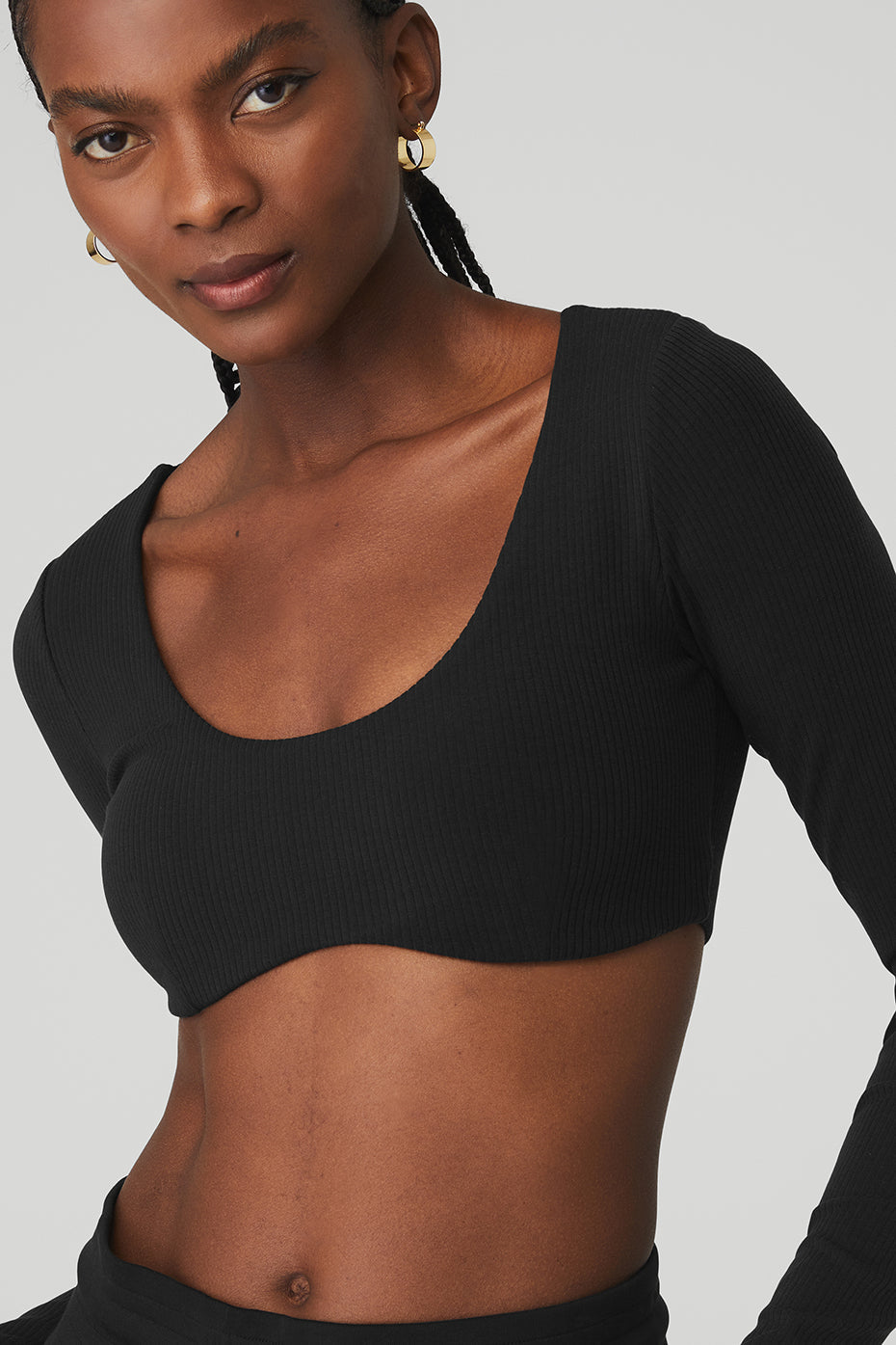 Ribbed defined long sleeve bra in black with scoop neck and cropped design, made from soft ribbed knit fabric.