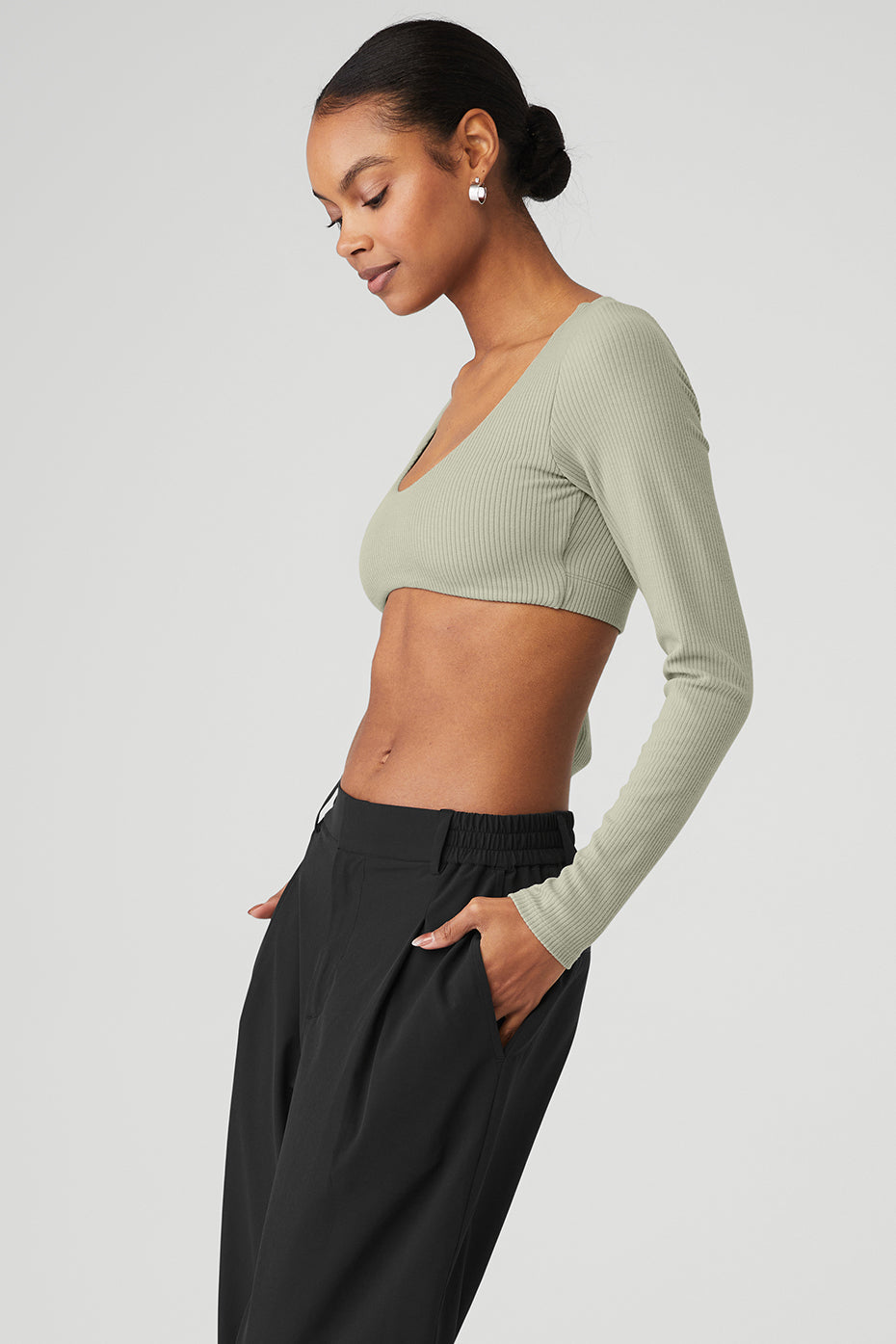 Model showcasing a ribbed defined long sleeve bra in green, featuring a cropped design and scoop neck.