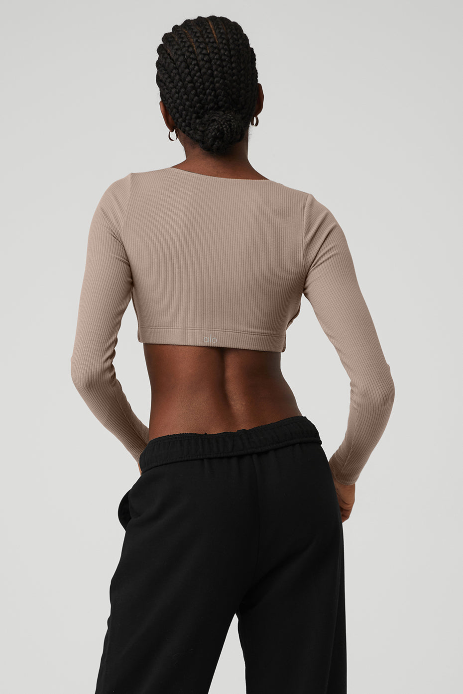 Ribbed Defined Long Sleeve Bra in beige, featuring a cropped design and soft ribbed fabric, worn with relaxed black pants.