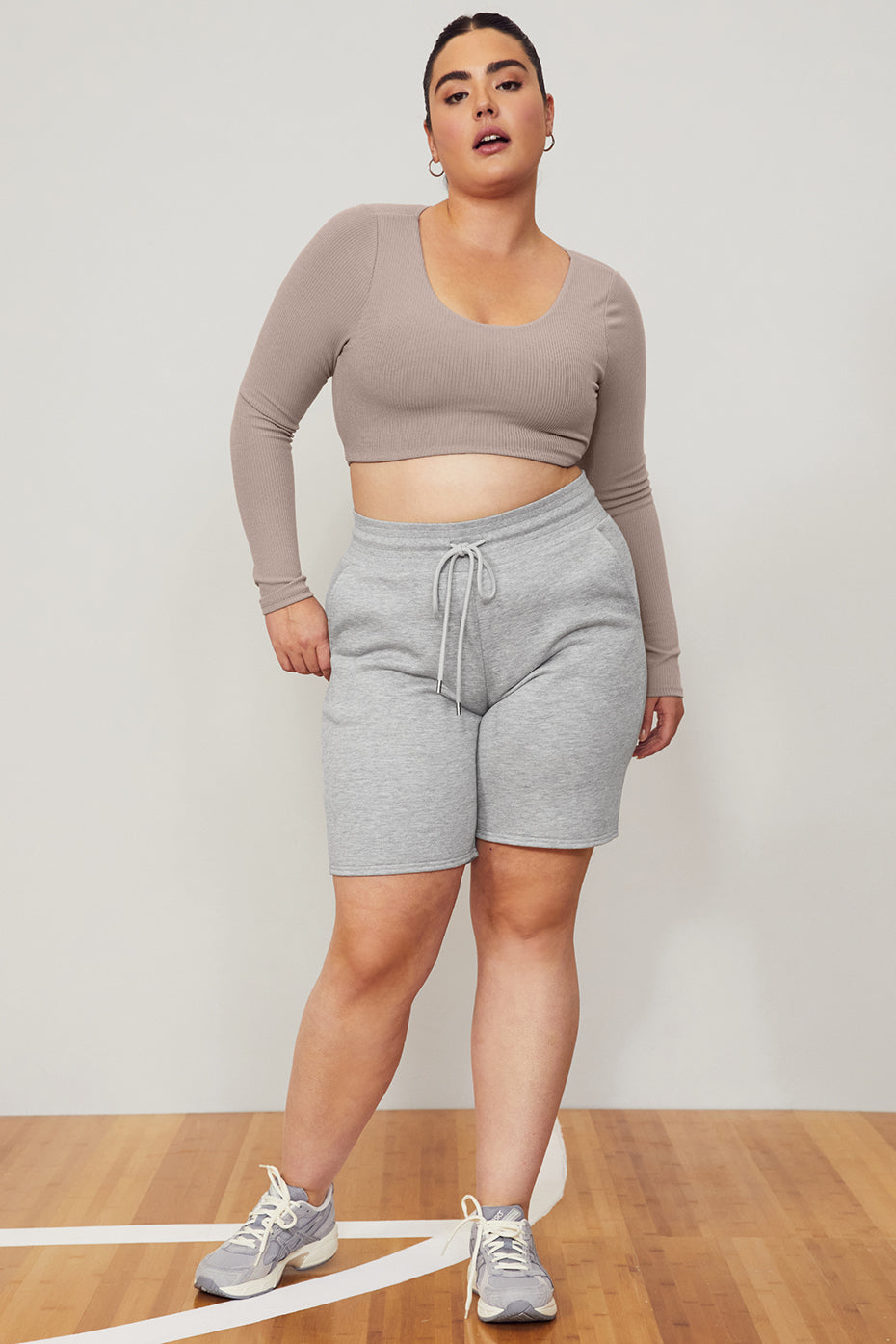 Model wearing Ribbed Defined Long Sleeve Bra with grey shorts, showcasing comfy ribbed fabric and flattering fit.