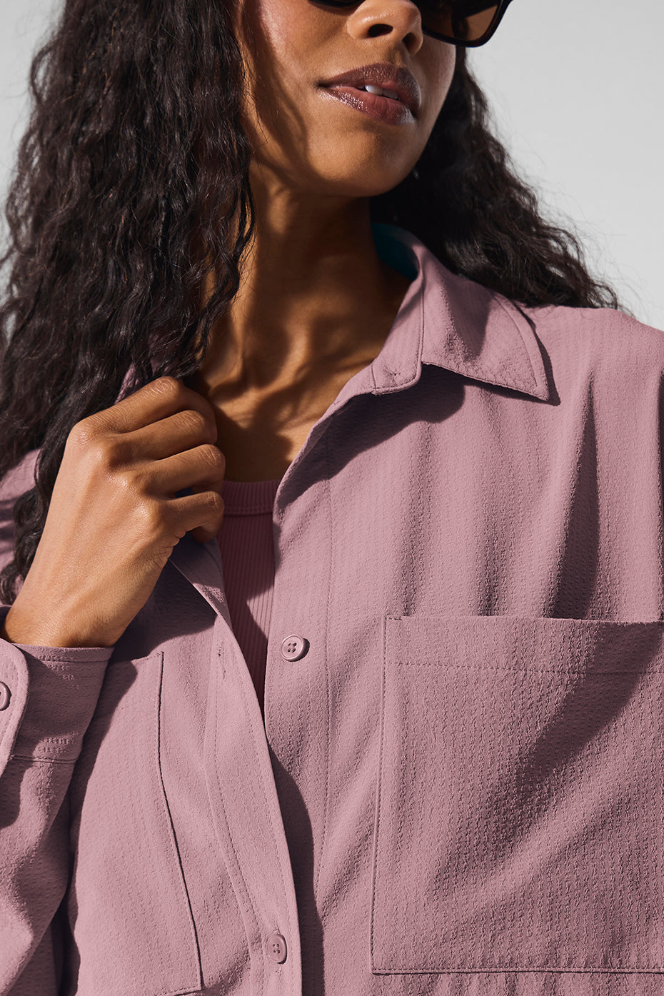 Close-up of a model wearing the Dreamscape Button Down Long Sleeve in pink with a casual pose and sunglasses.