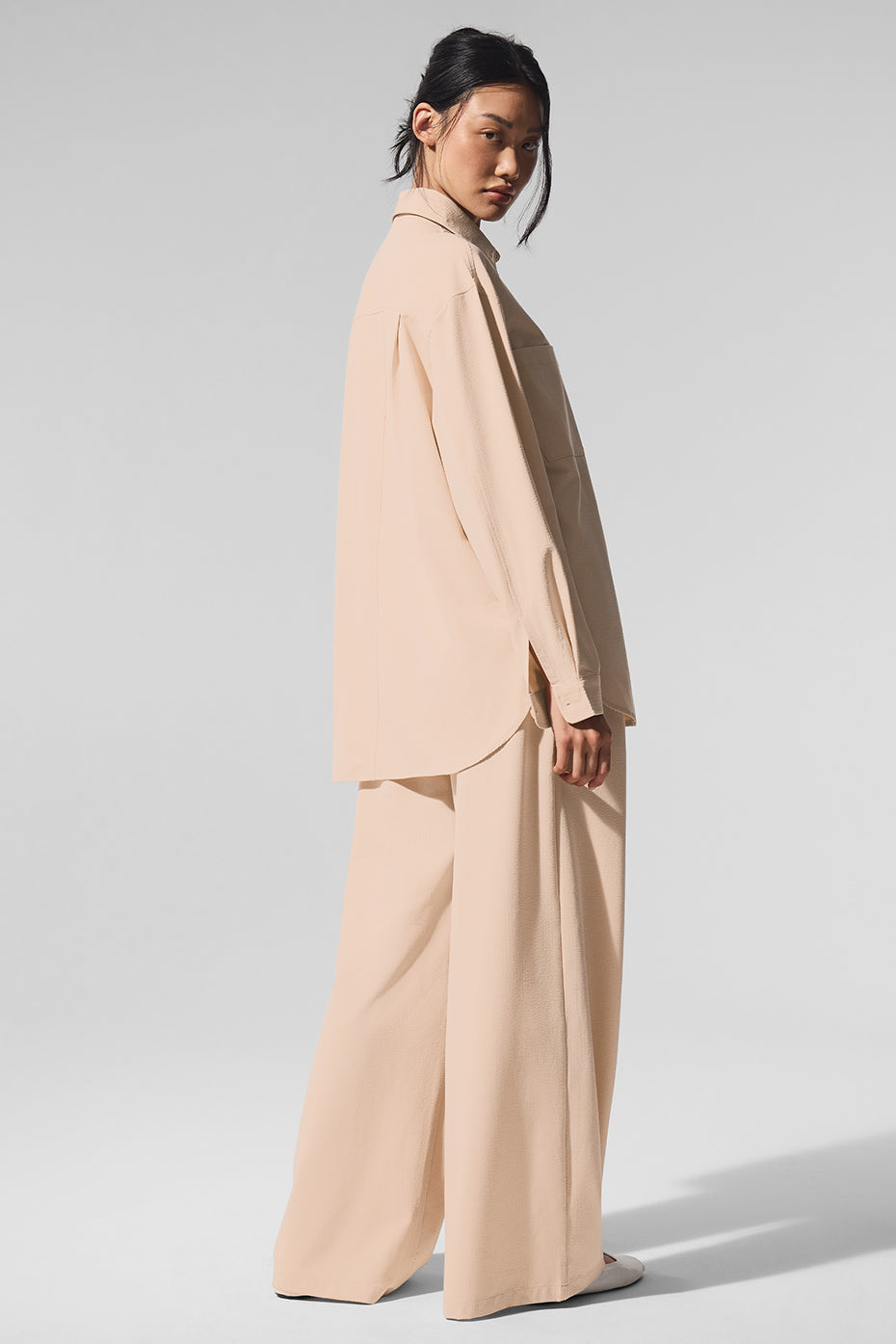 Model wearing Dreamscape Button Down Long Sleeve with High-Waist Dreamscape Trousers in a neutral tone.