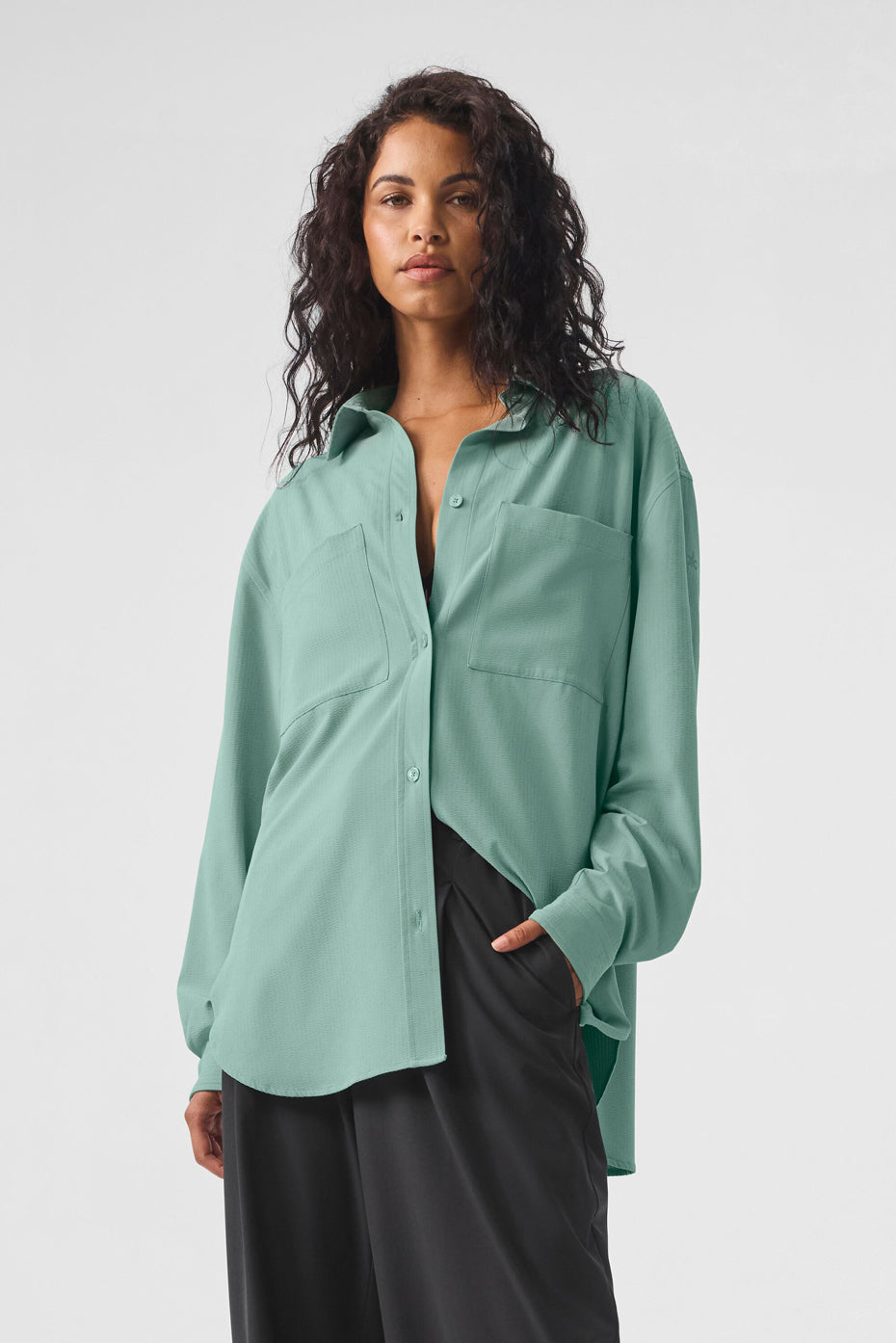 Model wearing Dreamscape Button Down Long Sleeve in teal, featuring front pockets and an oversized fit.