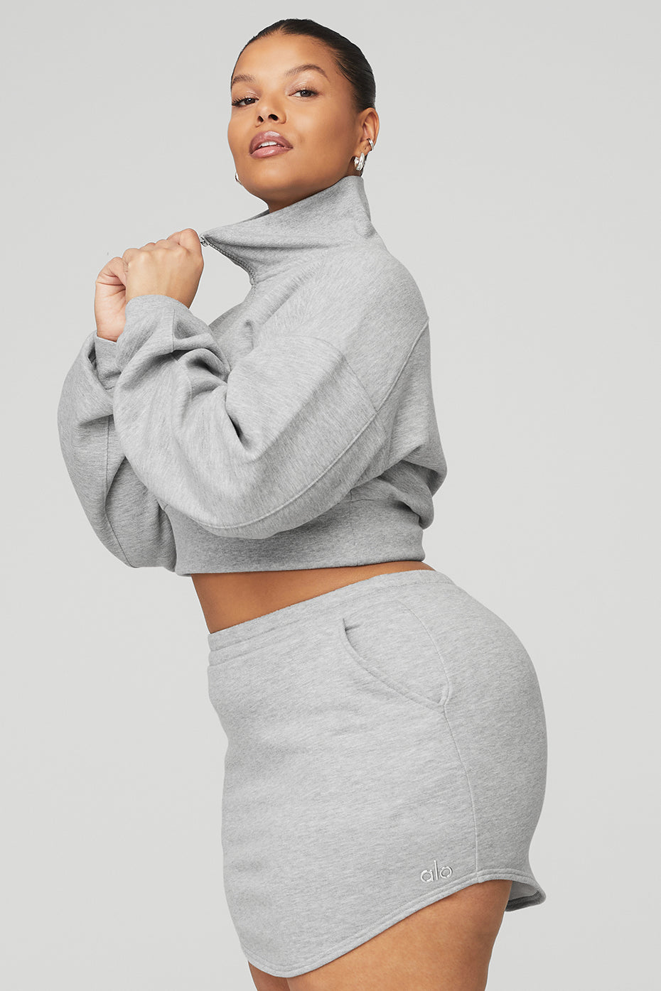 Model showcasing the Vixen Fleece 1/4 Zip cropped pullover and matching skirt in gray with a stylish high neck.
