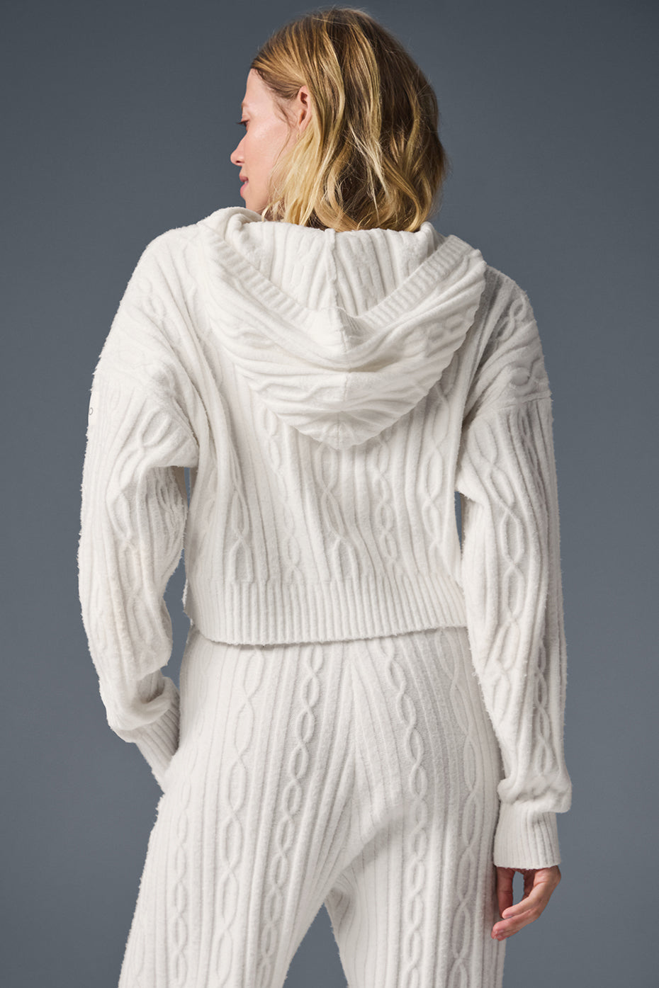 Back view of a woman wearing a cozy Cable Knit Winter Bliss Hoodie with a relaxed fit and cropped hem.