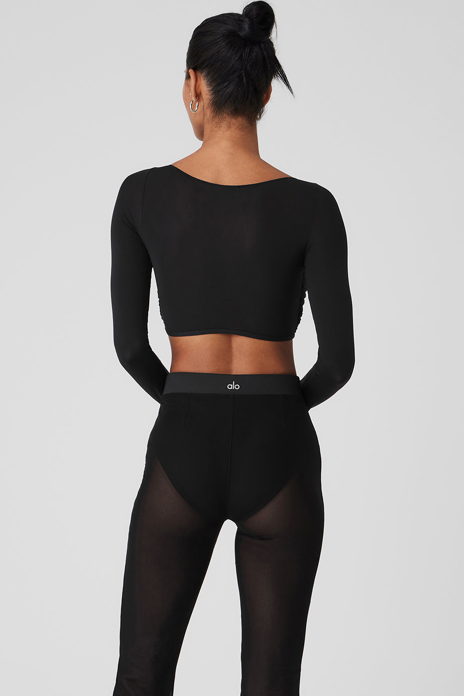 Model wearing a Mesh Sheer Illusion cropped long sleeve top and high-waisted black mesh pants from the back.