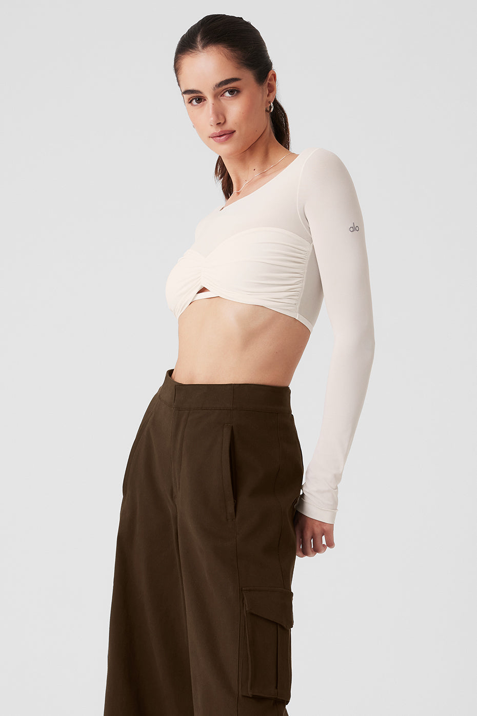 Model wearing Mesh Sheer Illusion cropped long sleeve with gathered front and keyhole cutout, paired with high-rise pants.