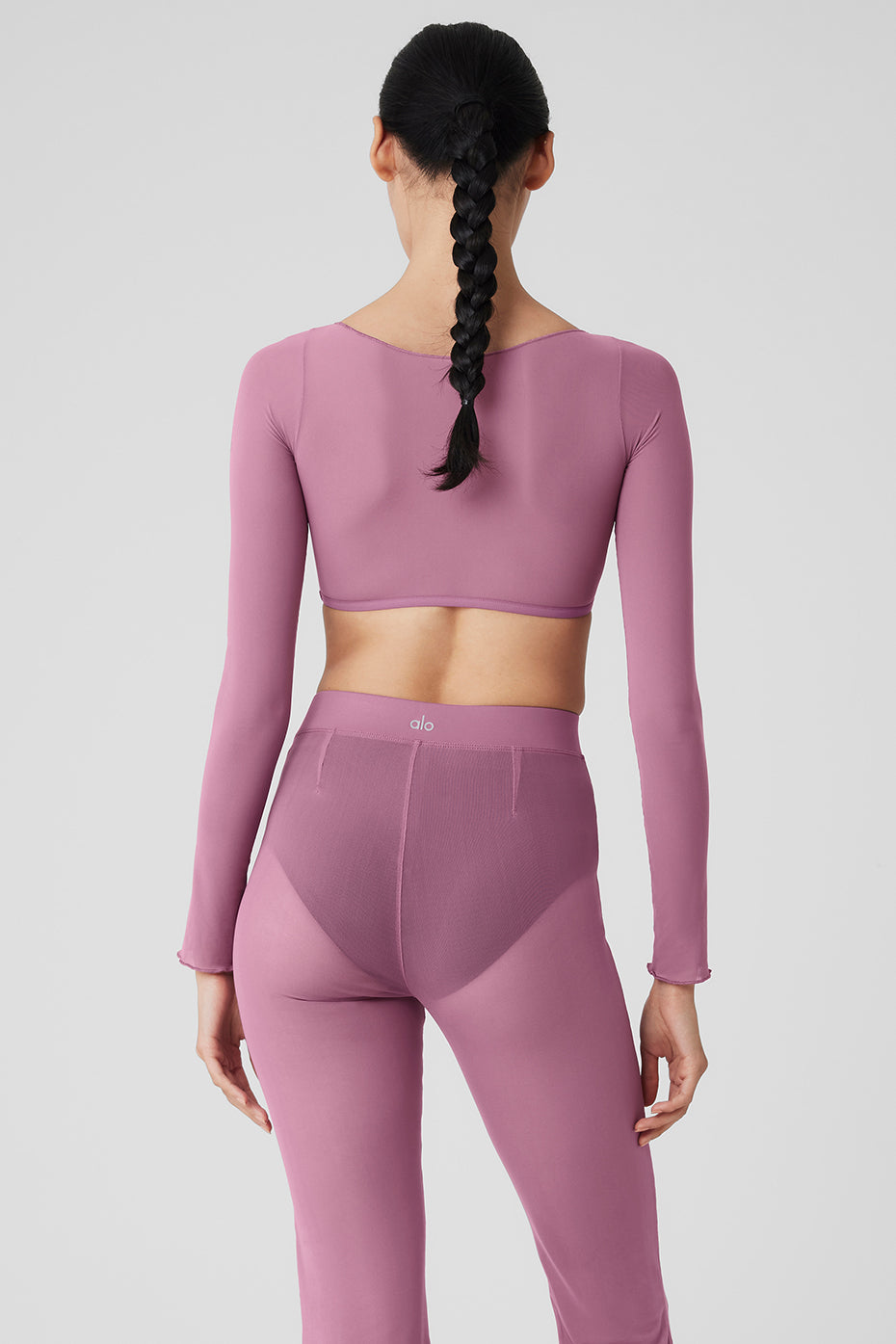 Mesh sheer illusion cropped long sleeve top in pink, featuring a boat neck and rib-grazing design, styled with matching pants.