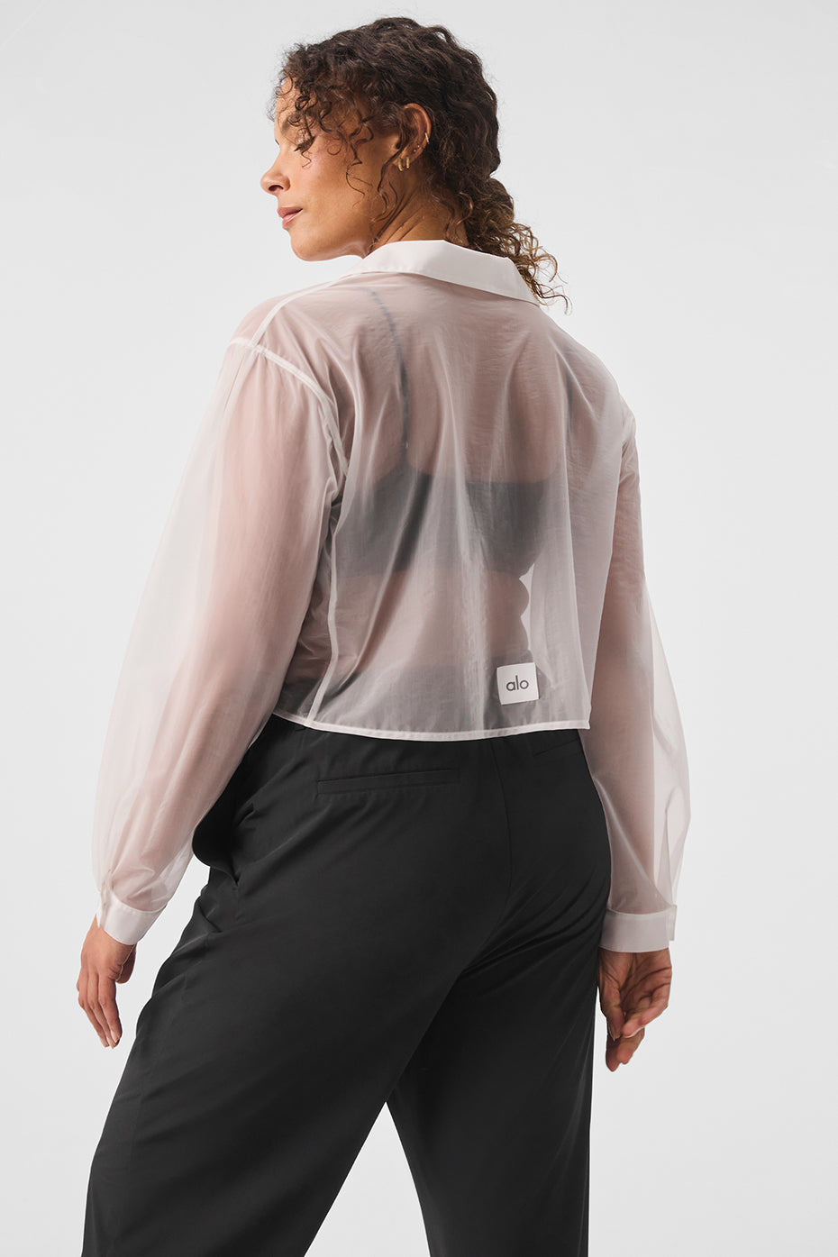 Model wearing sheer cropped Take Me Out button-up shirt with point collar and cuffs styled with black trousers.