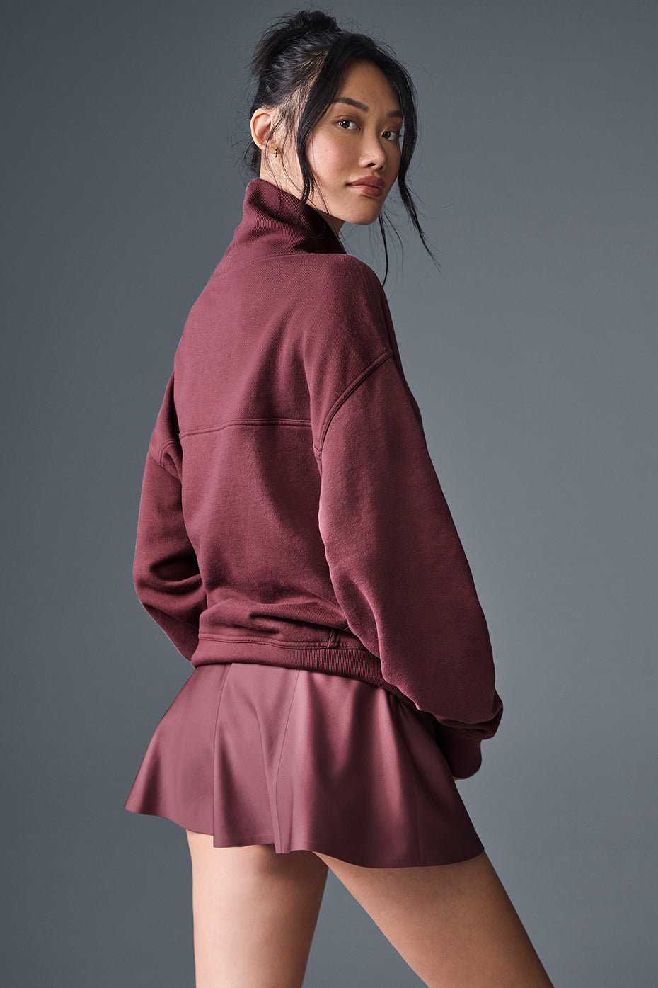 Hazy Mock Neck Pullover in burgundy worn with a matching pleated skirt, showcasing a soft oversized fit.