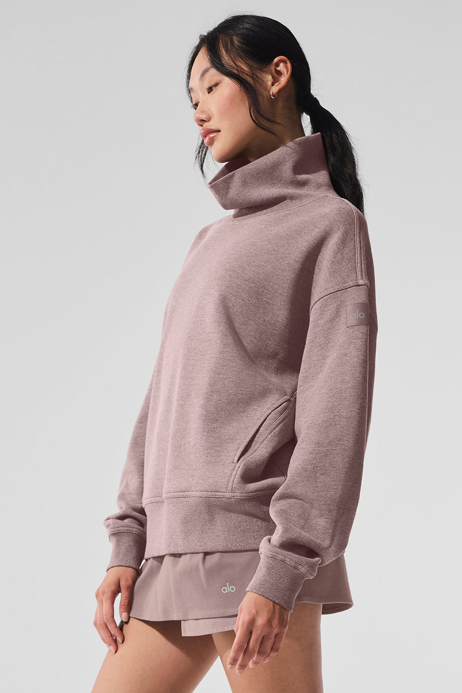 Hazy mock neck pullover sweater in soft pink with oversized fit, styled with a skirt for a casual look.
