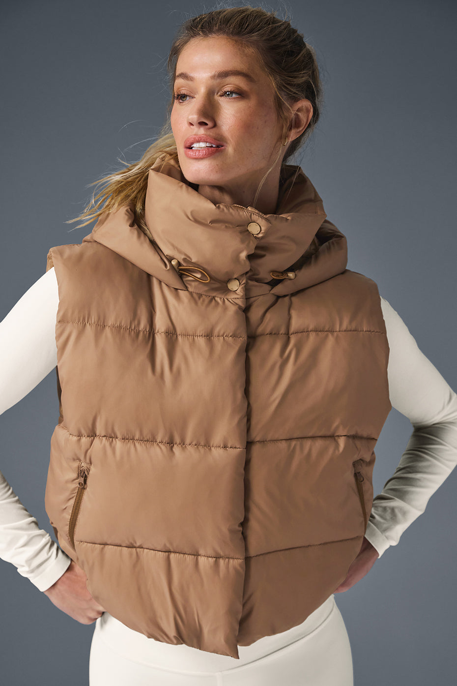 Gold Rush Puffer Vest featuring a tall hooded collar, cozy design, and cinched waist in a stylish brown color.