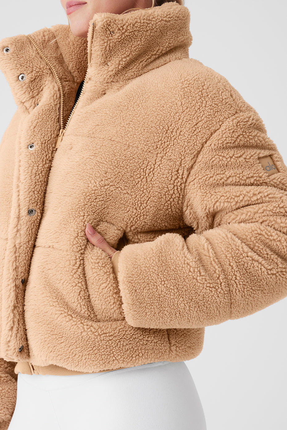 Sherpa Snow Angel Puffer in cozy tan with tall collar and zippered pockets for warmth and style.