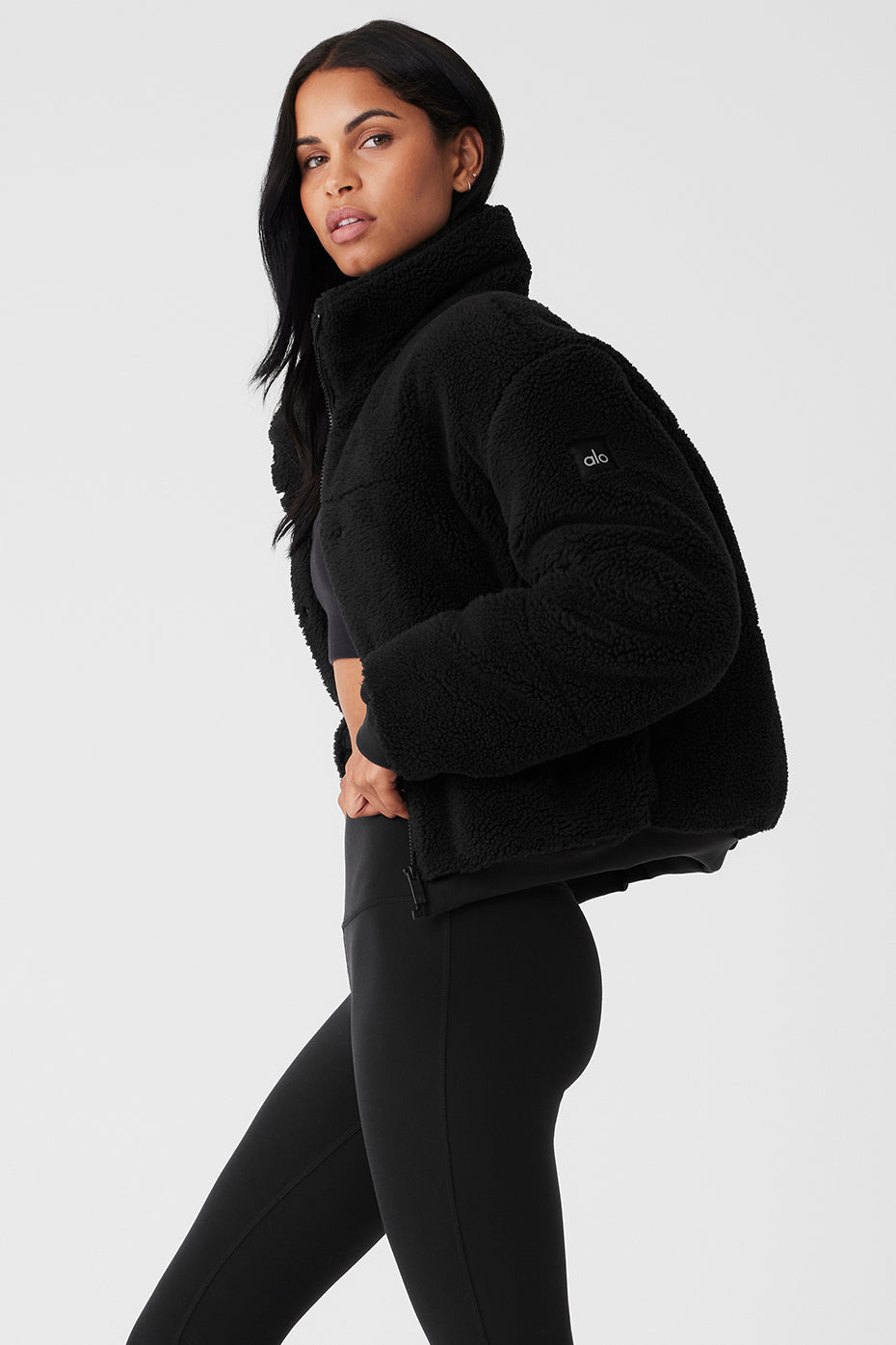 Sherpa Snow Angel Puffer in black, designed for warmth with tall collar and deep zippered pockets, perfect for layering.